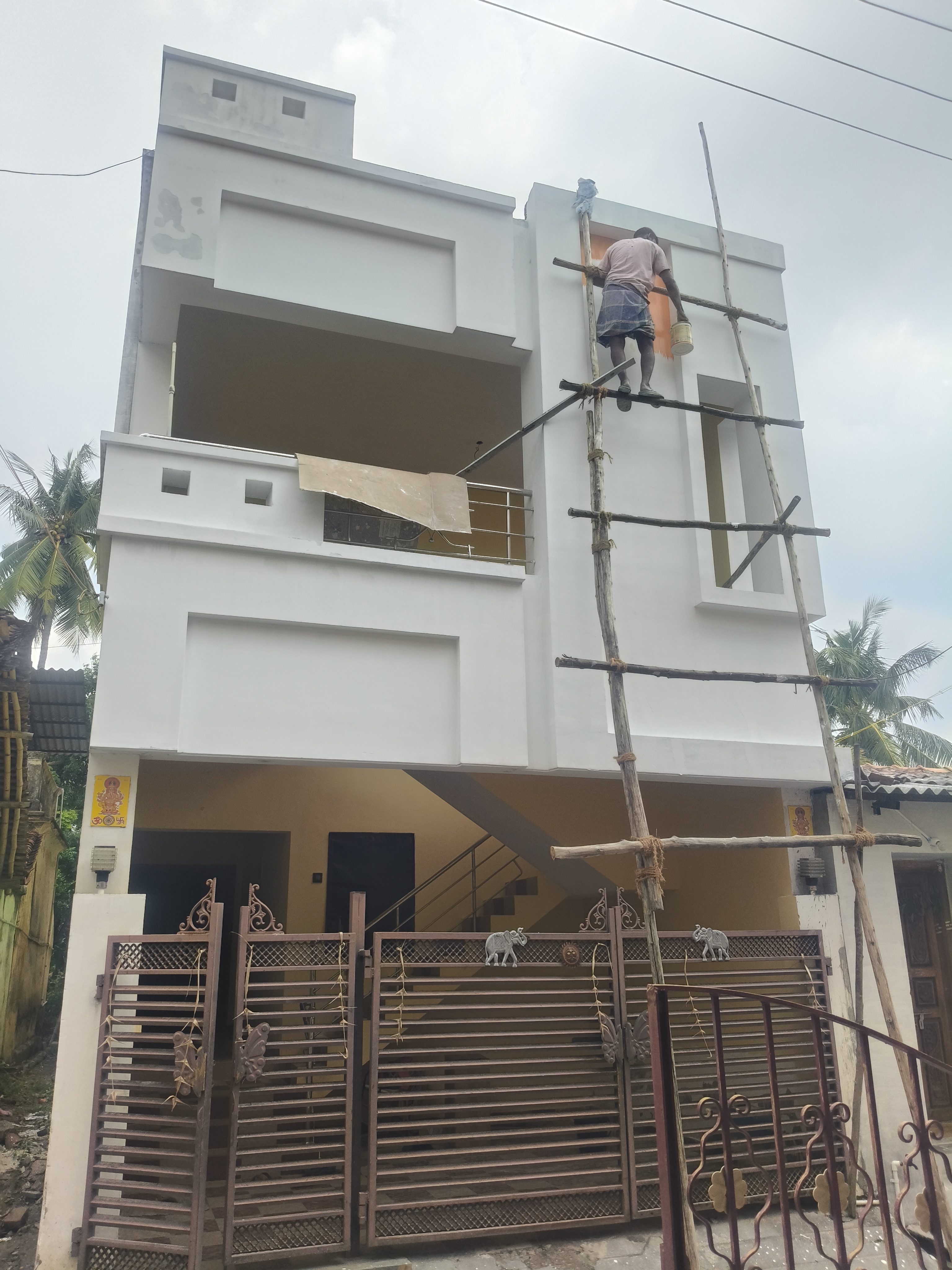 G+2 white residential home at final painting stage with ornate gate in Thiruvarur
